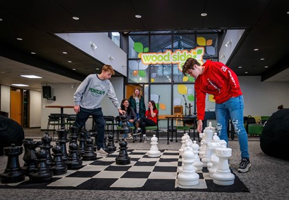 Two male students playing giant chess game in Woodside Cafe